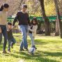 A family plays soccer together in a sunny park, enjoying quality time outdoors.